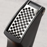 Garlic crusher utensil with fresh garlic cloves ready for pressing