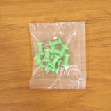 Multiple green push pins arranged showing sharp metal pins